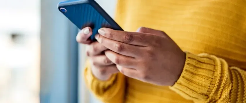 Person wearing a bright yellow jumper and holding a mobile phone.