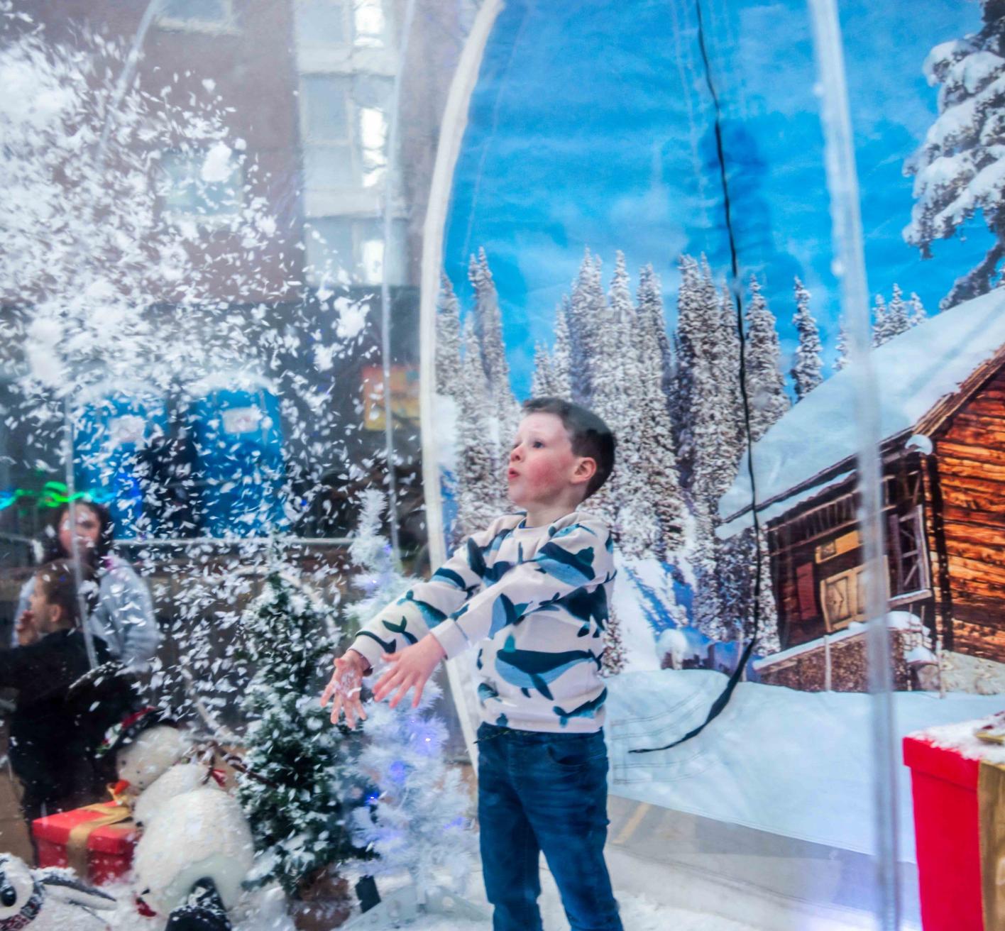 Child throwing snow inside a snow globe at Christmas event in Johnstone