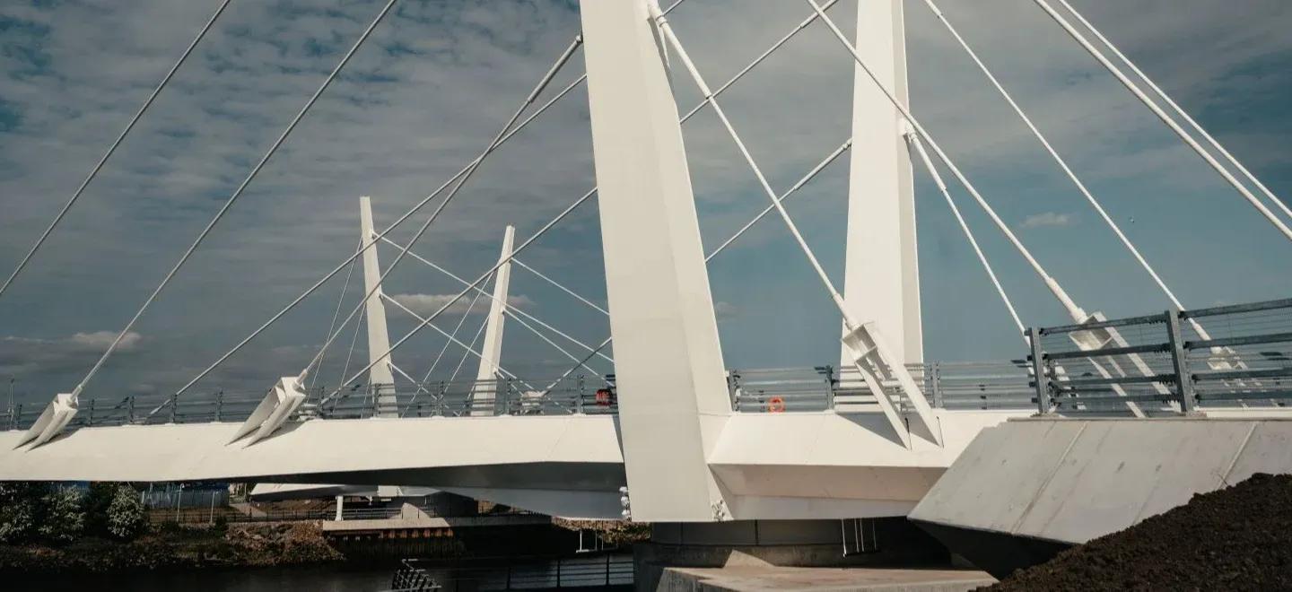 Renfrew Bridge, a white cable-stayed bridge with towers and support cables, over water on a cloudy day.