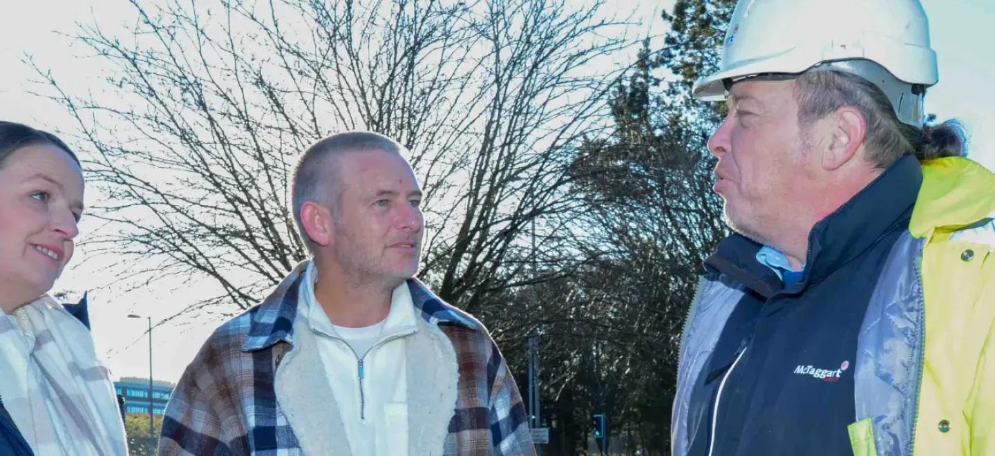 Two people talking to a construction worker