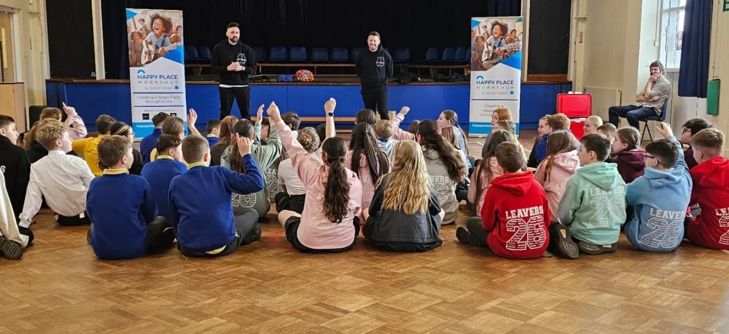 Pupils seated in gym hall raising their hands to talk with band members of SAINT PHNX.
