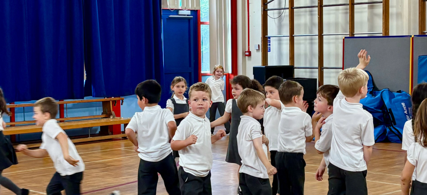 Primary school pupils in a gym hall with a teacher.