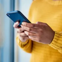 Person wearing a bright yellow jumper and holding a mobile phone.